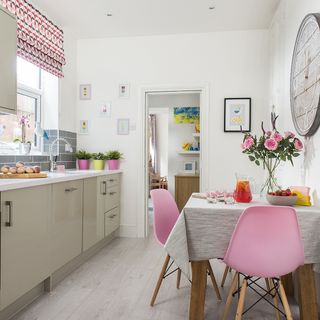 white kitchen with dining table and pink chairs