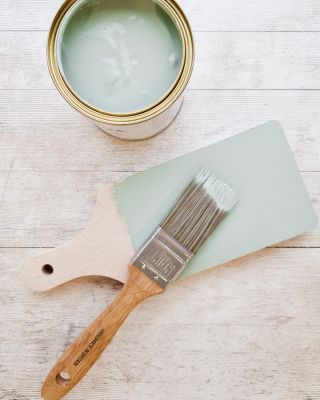 paint tin with brush and chopping board partially painted in sea green paint