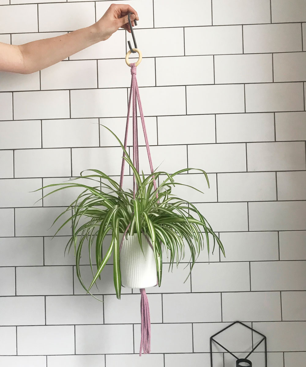 hand holding hanger with wooden ring tied to macrame plant hanger