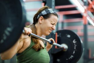 Young woman lifting weights in gym