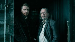 Jack Lowden and Gary Oldman in standing in a doorway looking towards the camera in Slow Horses Season 6