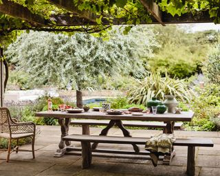 alfresco dining scene with OKA-UK Conisbrough Dining Table and Gullion Bench 2022 Garden Collection