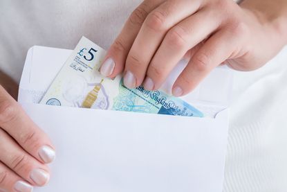 Person taking £5 note out of a white envelope