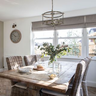 Oak dining table and wicker dining chairs in rustic style dining area with garden views