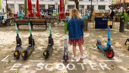 A young woman at an e-scooter stand