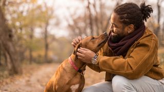 Man petting dog outside in the woods