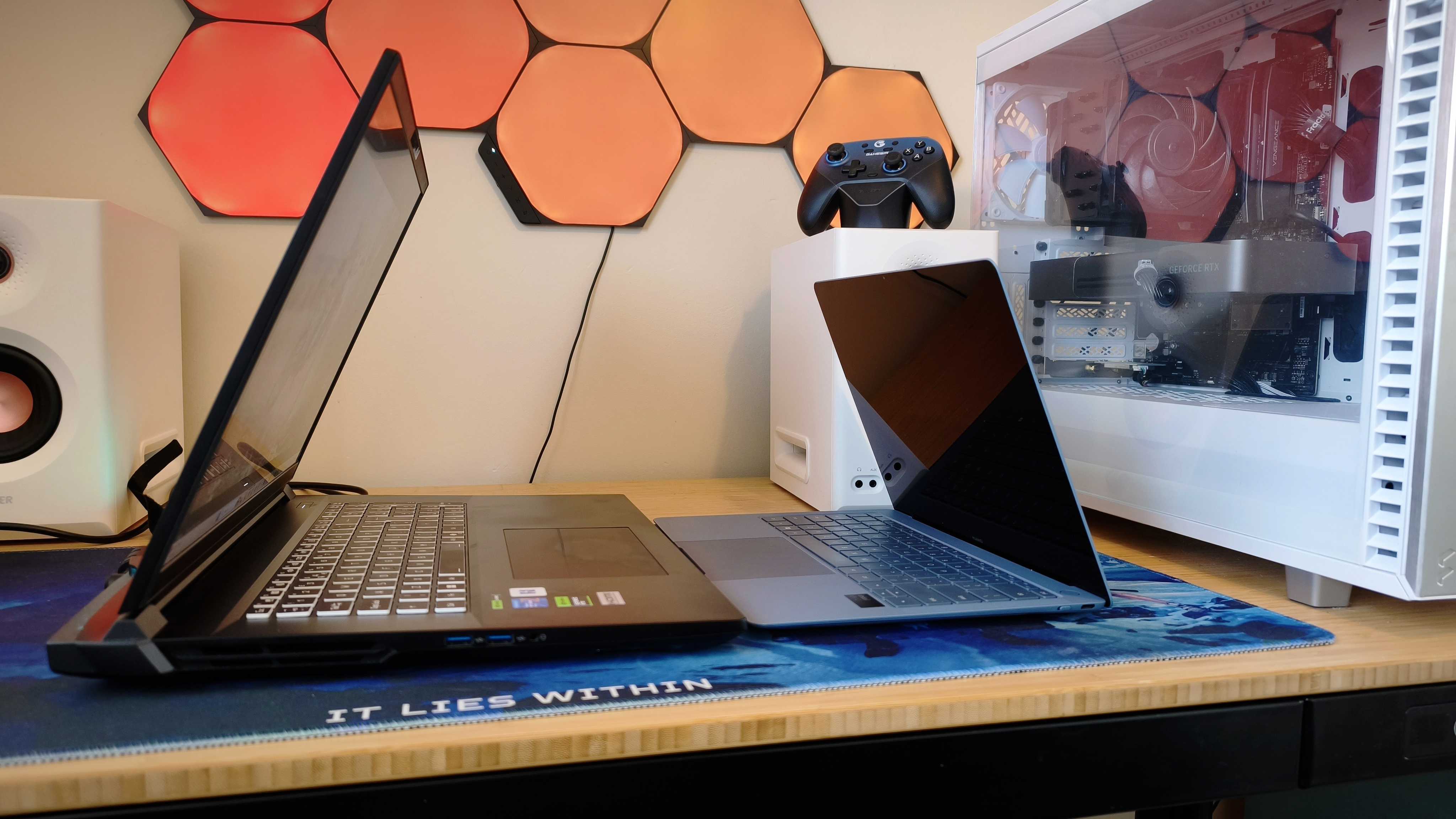 A black Overclockers Pinnacle laptop on a wooden desk opposite a Huawei Matebook X Pro