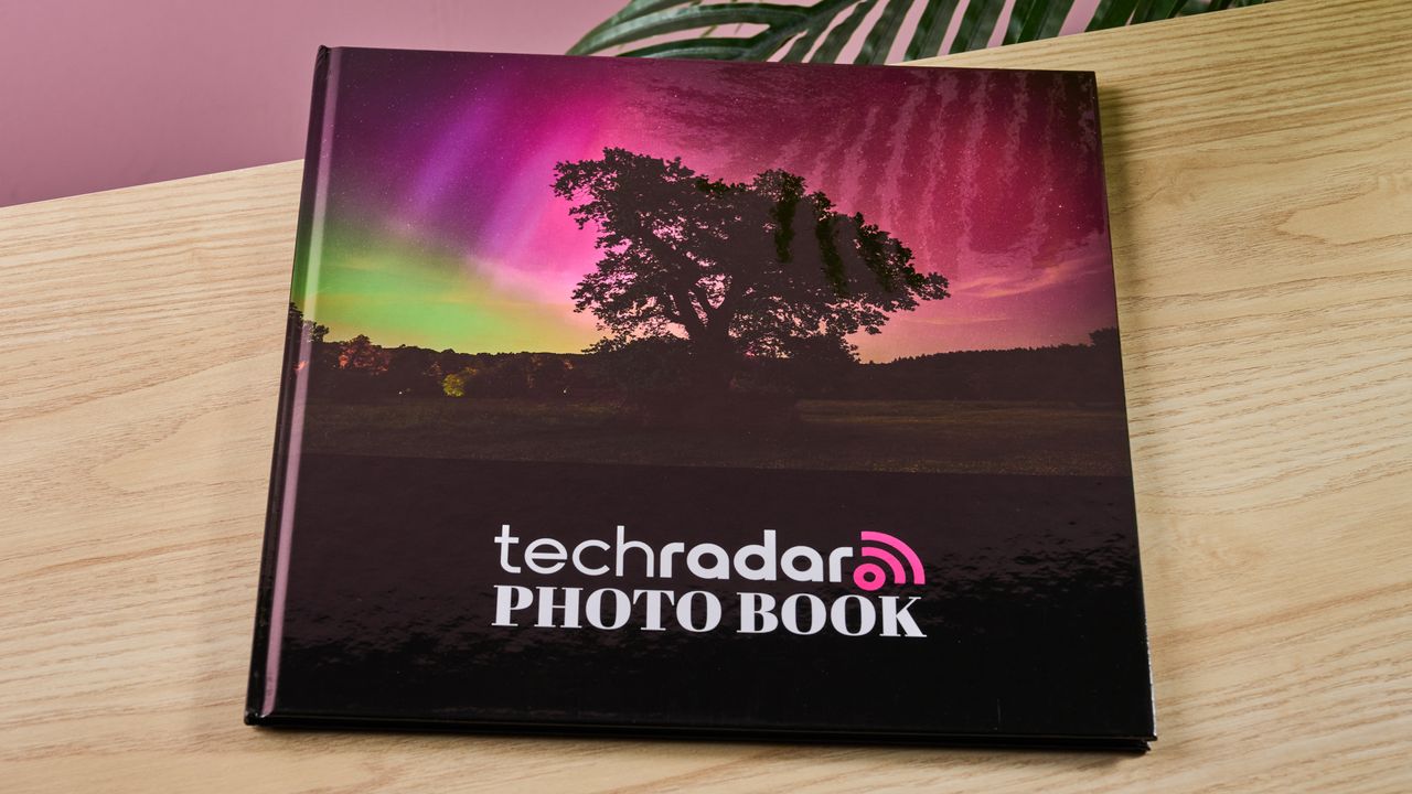 VistaPrint photo book on table with pink wall and plant in background
