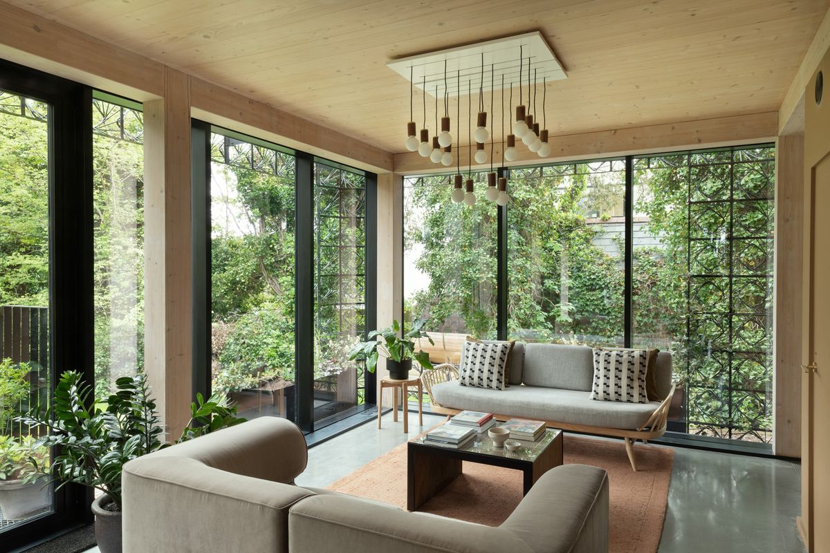A lounge with large glazed window, two grey sofas and a statement pendant light