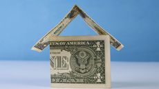 Dollar bills in the shape of a house with a blue background