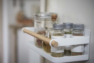 metallic spice rack on side of refrigerator, with spices inside, white with wooden rail