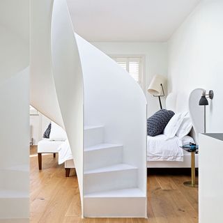 bedroom with wooden flooring and white staircase