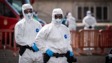 Two people in hazmat suits evacuating the hantavirus cruise ship