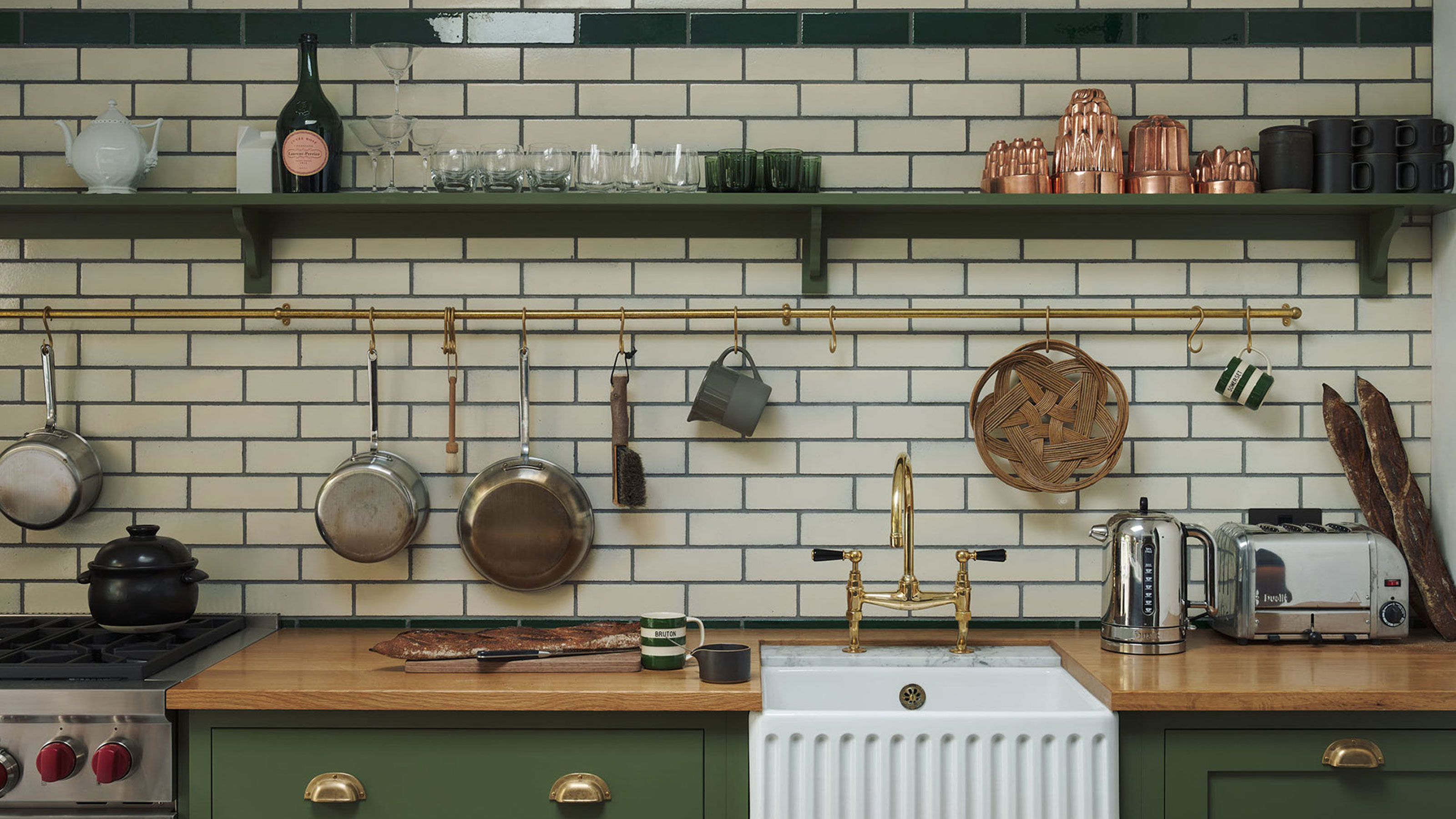 rustic green kitchen with wooden worktops and metro tiles on the wall with pot hanging racks and ceramic sink