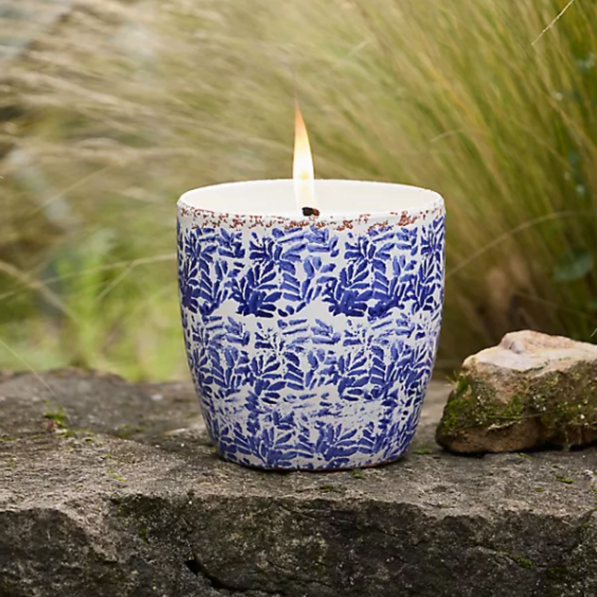Blue and white porcelain candle with grasses and natural stone in background
