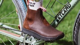 A brown chelsea boot clipped into a sage green bike