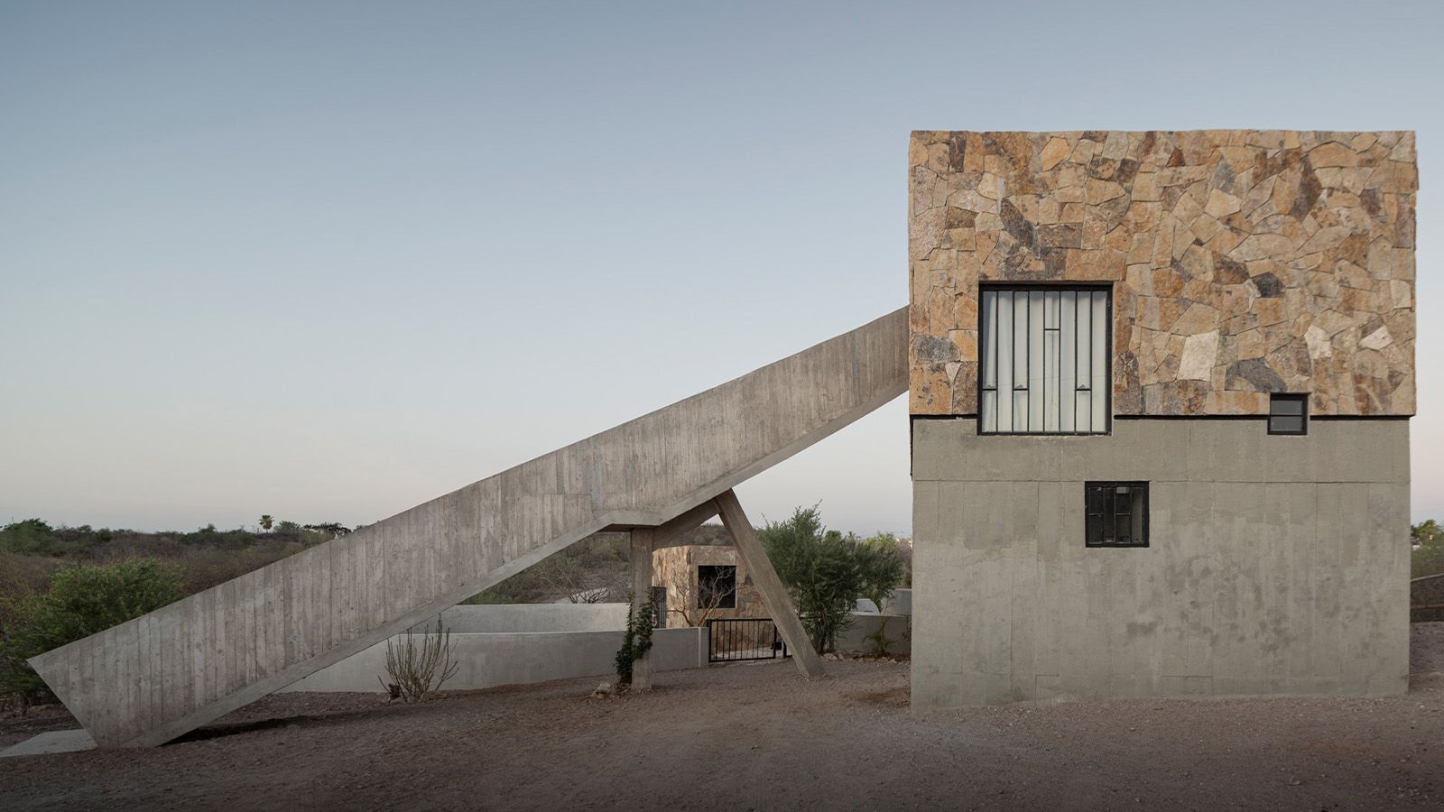 Concrete house with tilted concrete ramp-like structure to first floor