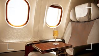 An airline seat with a glass of champagne on a table