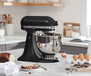 A KitchenAid Artisan Stand Mixer on a countertop with baking ingredients around it