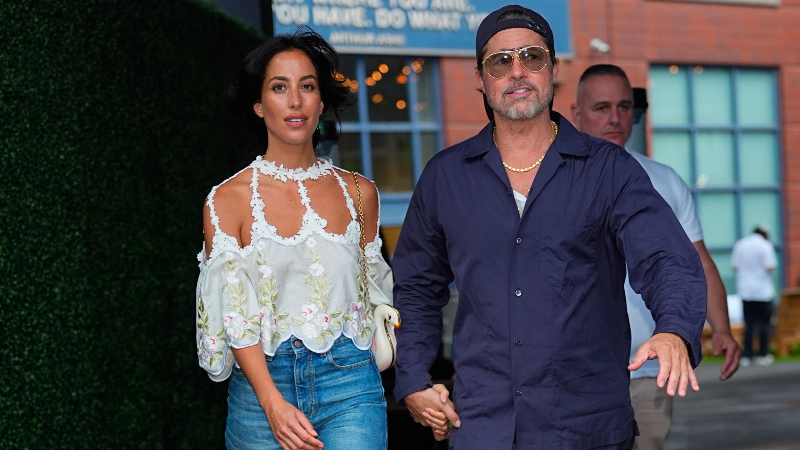 Ines de ramon wears a white floral top and jeans. brad pitt wears a navy blazer and sunglasses.