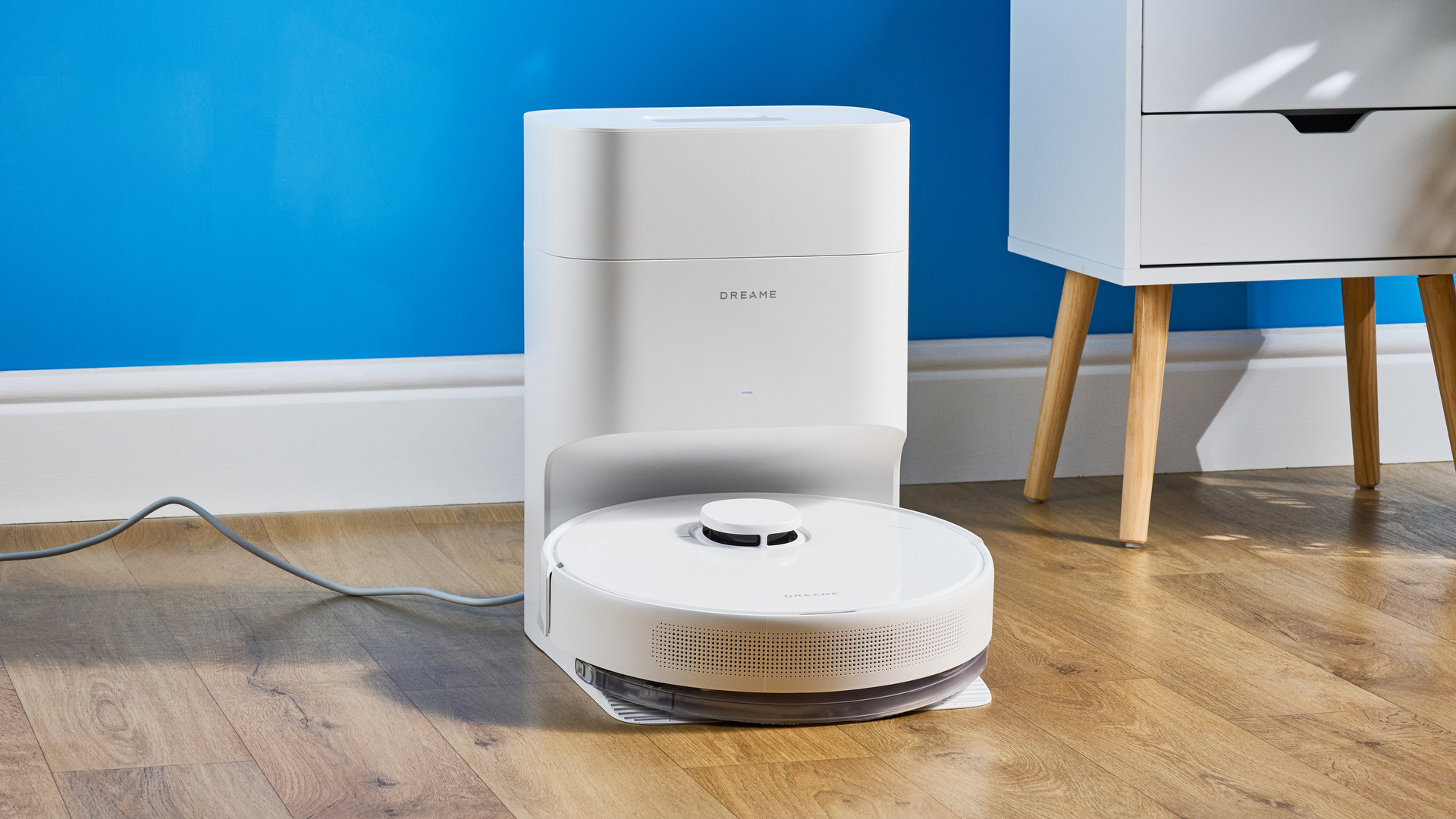 Dreame D10 Plus Gen 2 photographed on a wooden floor in front of a blue backdrop