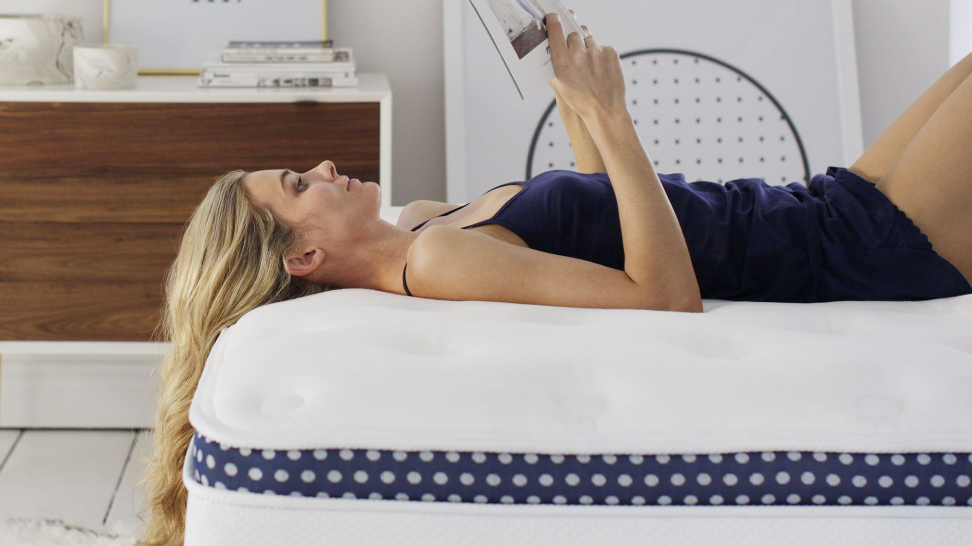 A woman with blonde hair lies on a Winkbed Mattress while reading