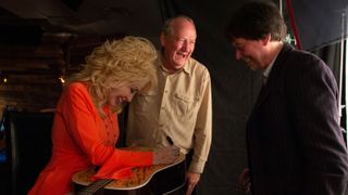 Dolly Parton, with Dayton Duncan (center) and Ken Burns, signs one of the Martin guitars provided for Country Music.