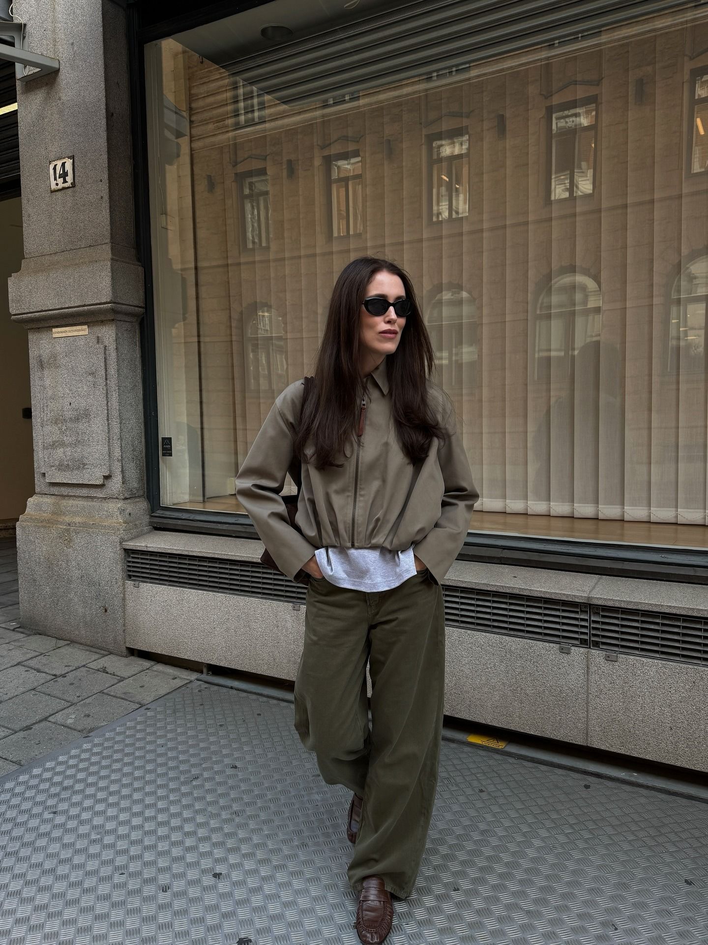 A woman posing on the street in an autumnal outfit with deep espresso brown hair