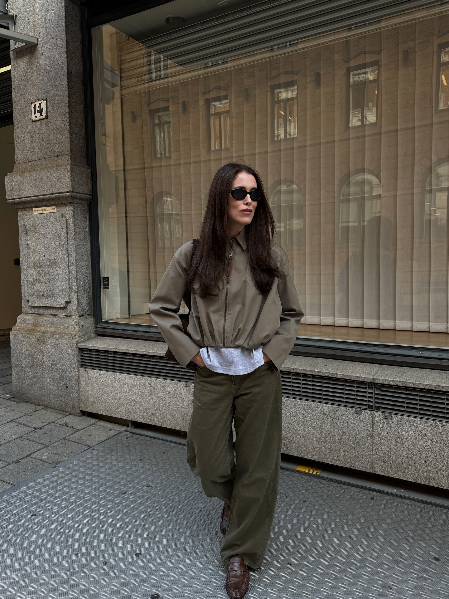 A woman posing on the street in an autumnal outfit with deep espresso brown hair
