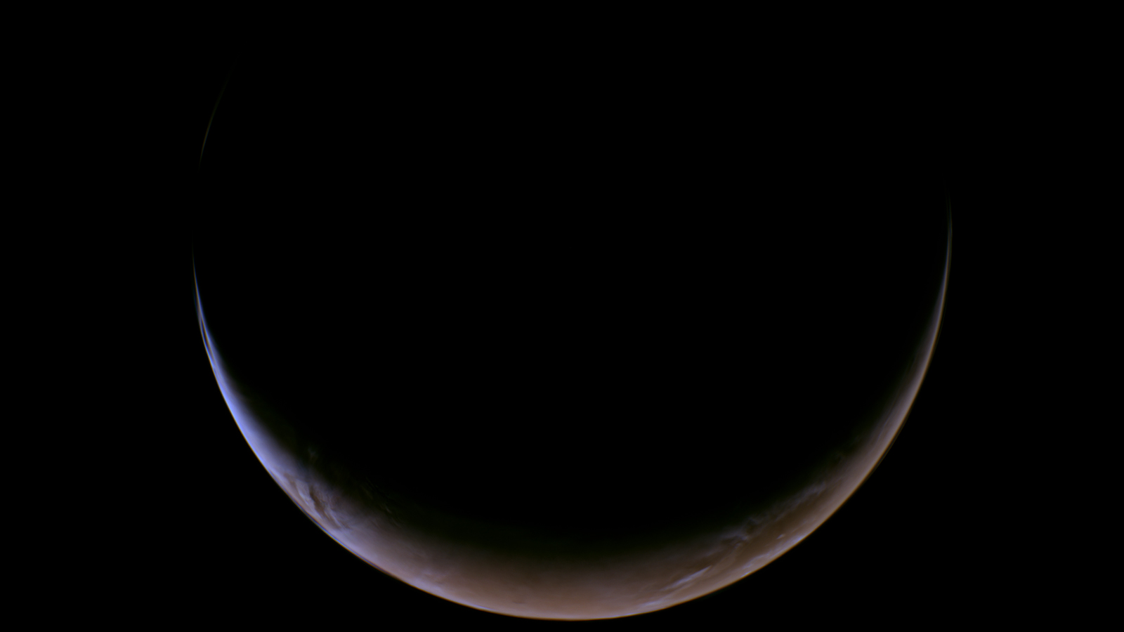An image of Mars captured by NASA's Psyche spacecraft that shows the entire planet but in the shape of a crescent thanks to a thin slice of sunlight at the bottom of the planet