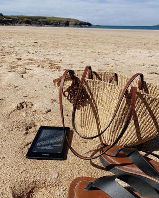 @emilyjdawes picture of M&S flip flops on a beach with Loewe raffia bag