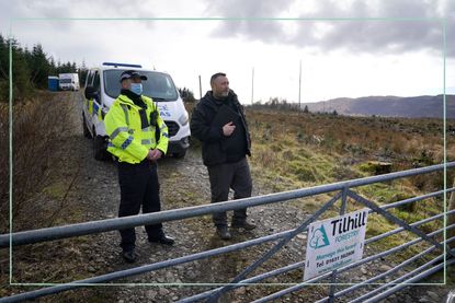 Police investigating the murder of Lynda Spence stood behind a fence in a remote location in Scotland