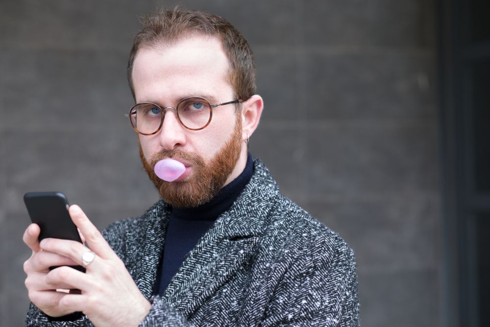 A man chewing gum while holding a mobile handset device