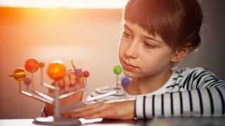 A young girl looks at a model of the solar system.