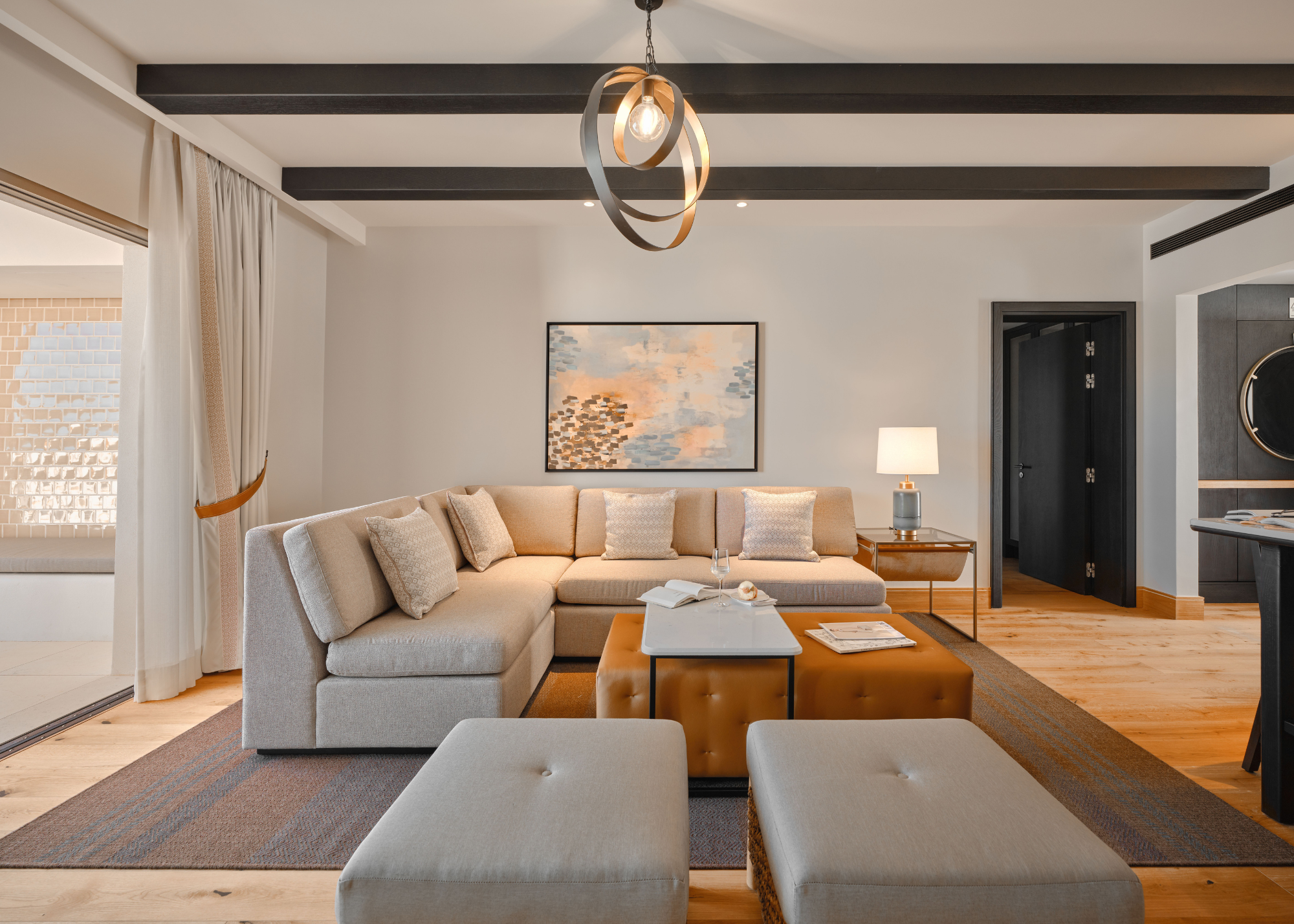A living room with a large L-shaped sofa. A pendant light hangs in the middle of the room. 