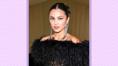 Olivia Rodrigo wearing a black feathered and lace bodysuit as she attends The 2021 Met Gala Celebrating In America: A Lexicon Of Fashion at Metropolitan Museum of Art on September 13, 2021 in New York City. / on a lilac background