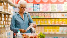 Shocked senior customer holding a long expensive grocery receipt.