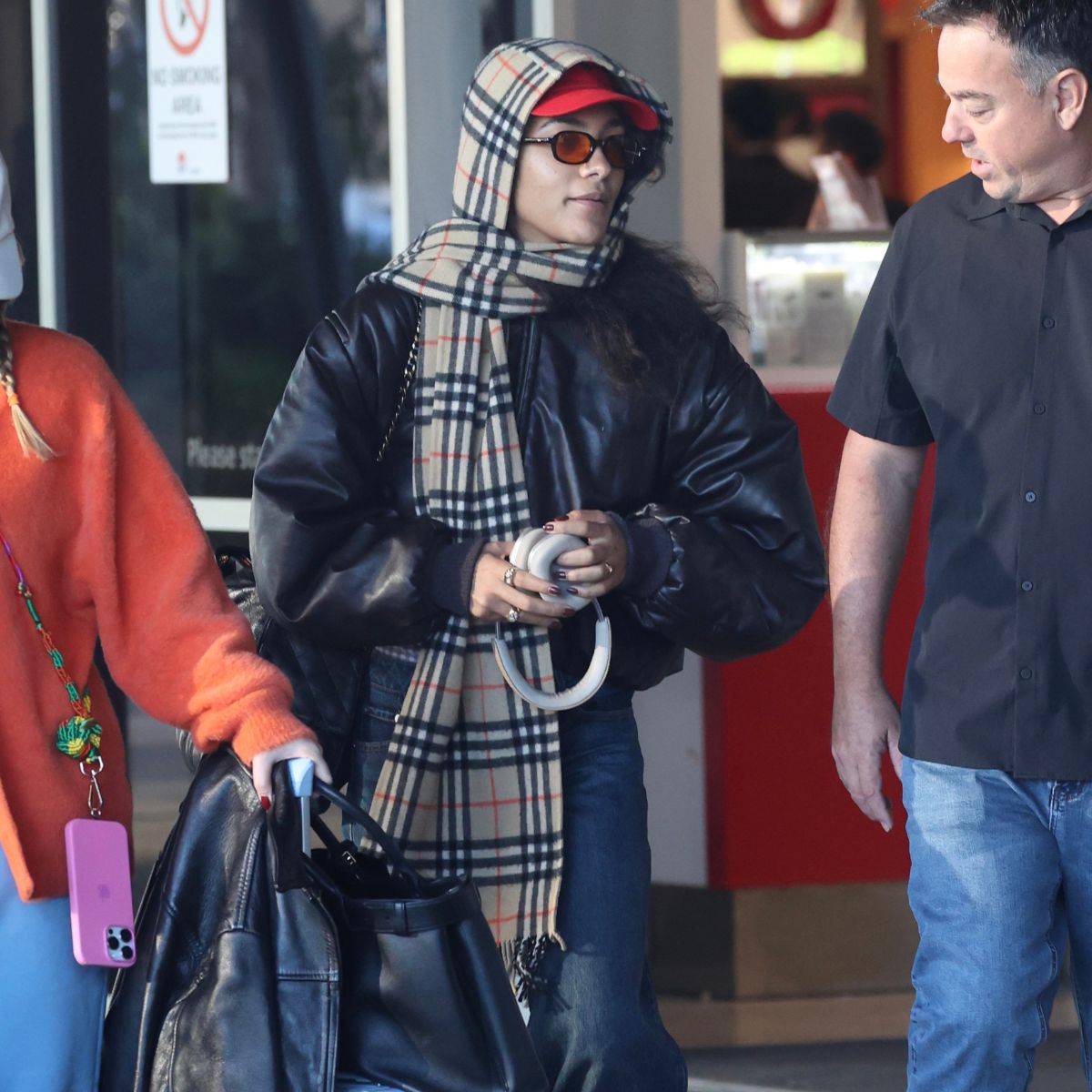 An image of Olivia Dean wearing a leather bomber jacket and barrel-leg outfit to Sydney Airport. 