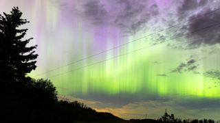 Northern lights appearing as a vibrant green ribbon of light in the sky. 