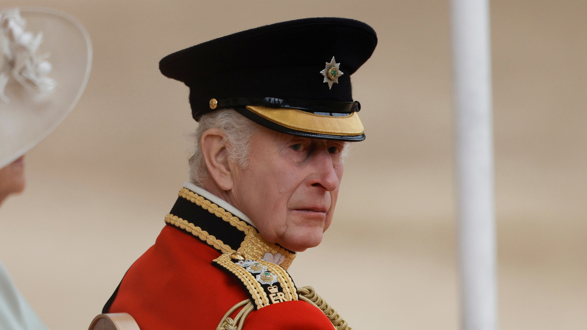 King Charles wears red military uniform and a black hat at Trooping the Colour