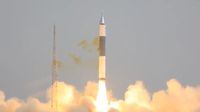 a white and black rocket launches into a gray sky