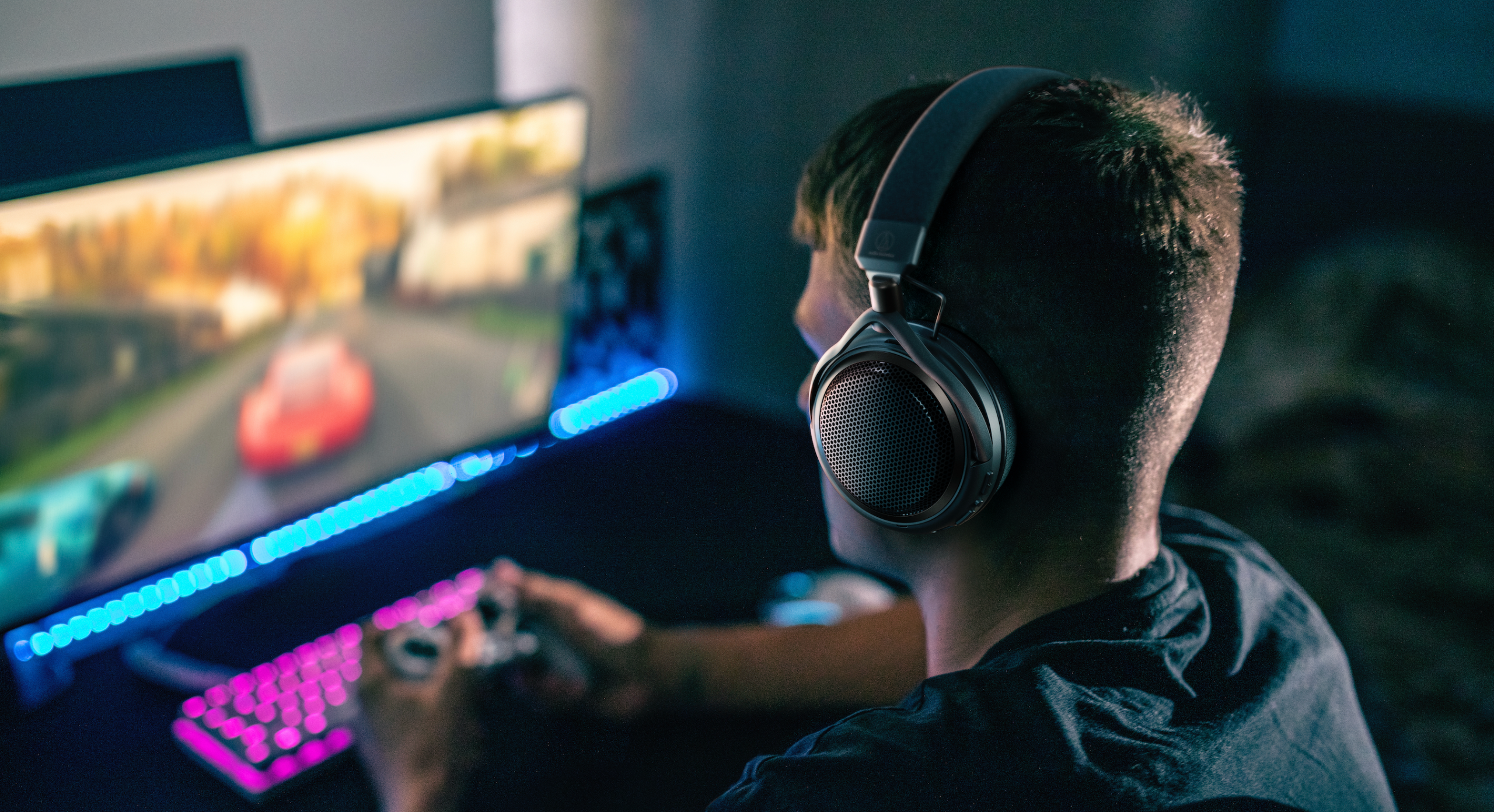 Audio-Technica headphones in muted lighting, worn by a man while gaming and also on a briefcase