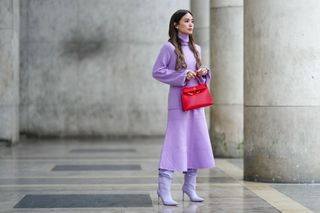 woman in purple oversized sweater, purple skirt, purple boots, and pink bag