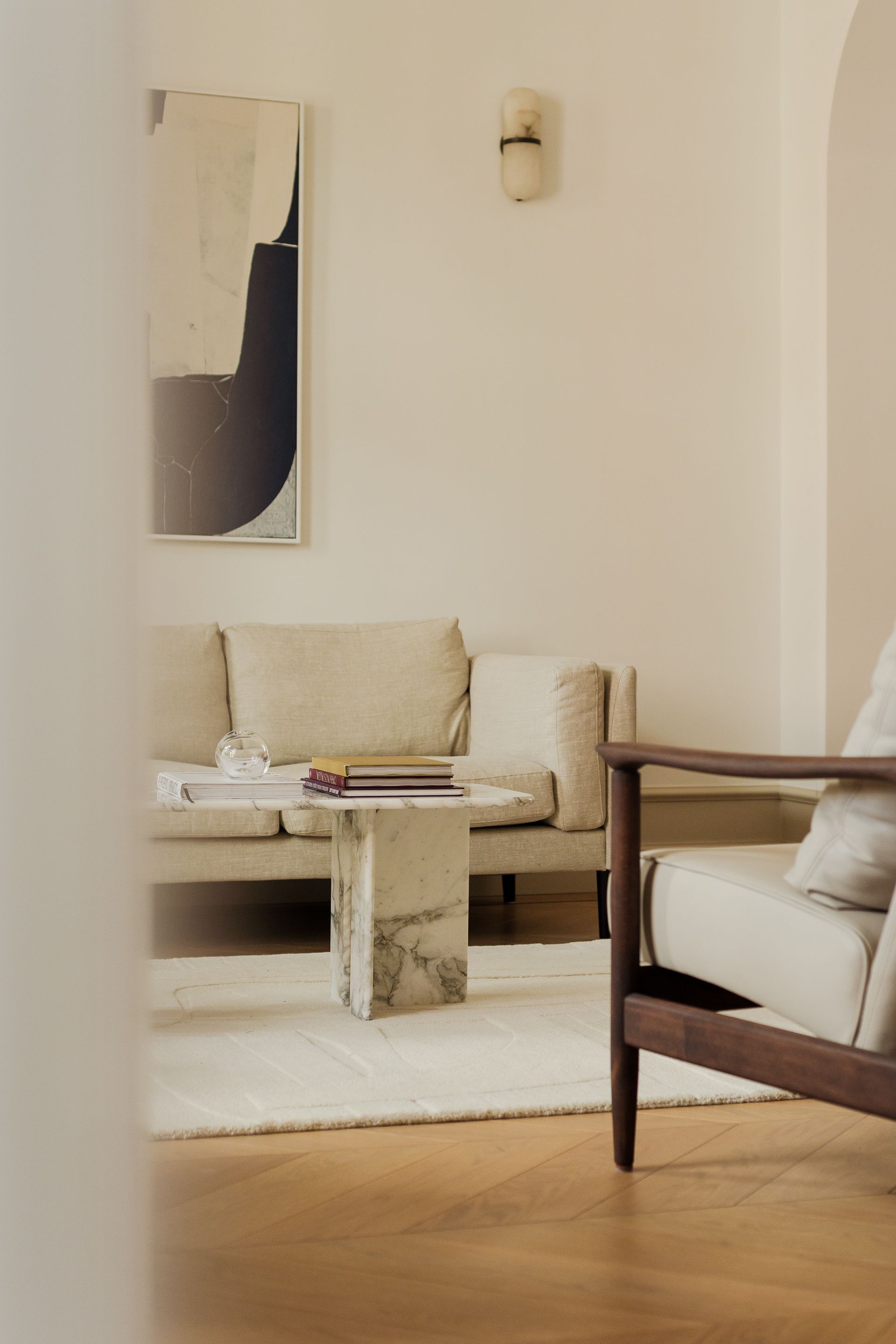 A living room with a muted sofa and a white artwork above