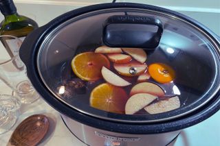 Mulled wine being made in a slow cooker with lid on and spoon to one side