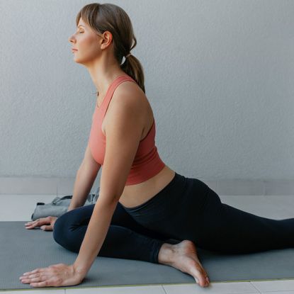 Best exercise mats - Woman in peach colored sports bra and black leggings practising yoga on exercise mat