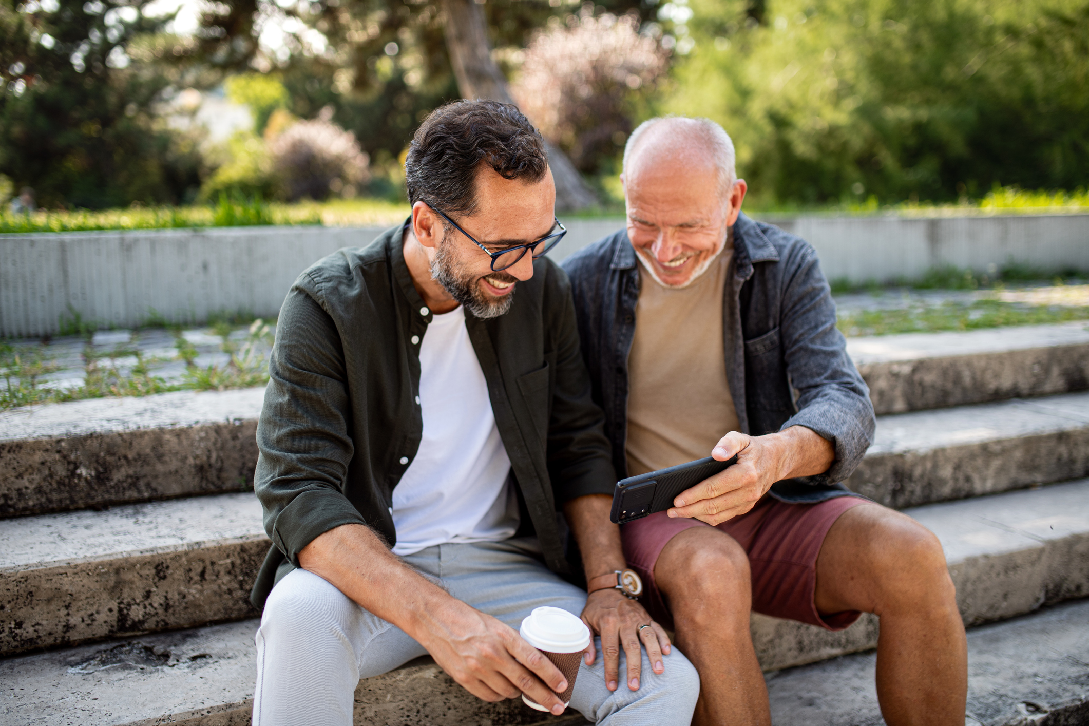 A photo of a retired baby boomer and a younger adult looking at something on a mobile phone.