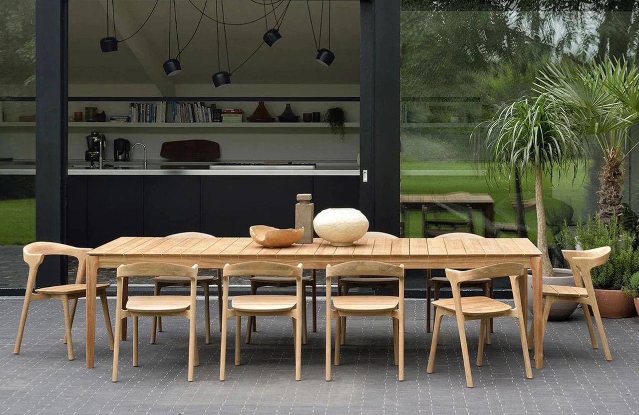 A large teak outdoor dining table and chairs