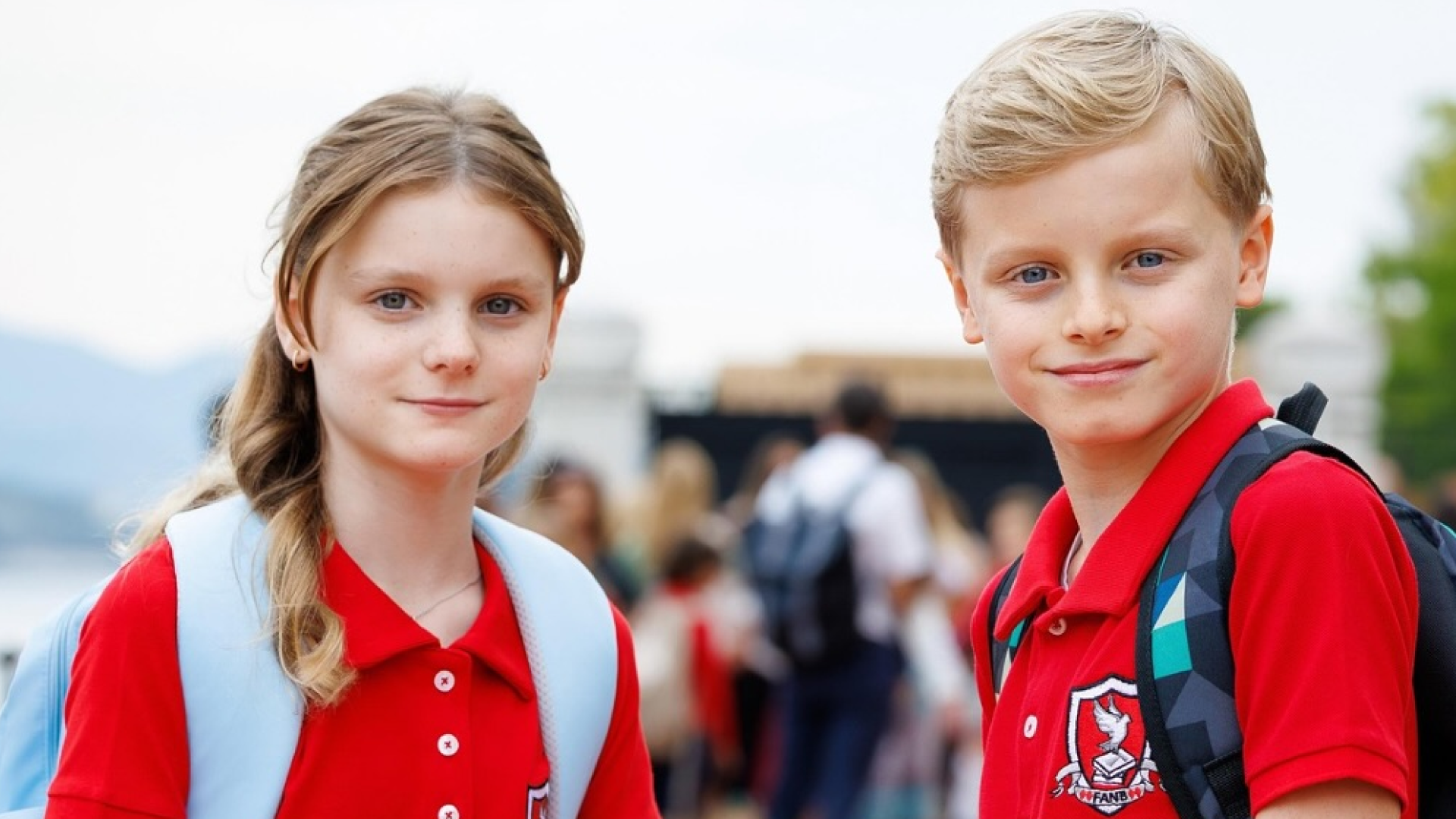 Princess Gabriella and Prince Jacques posing in red school uniforms and backpacks