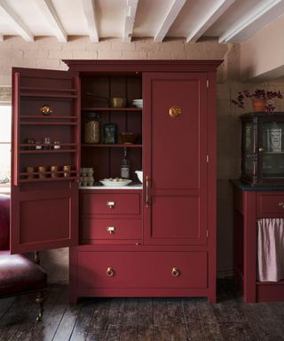 burgundy red kitchen freestanding pantry unit with brass hardware and spice racks by deVOL